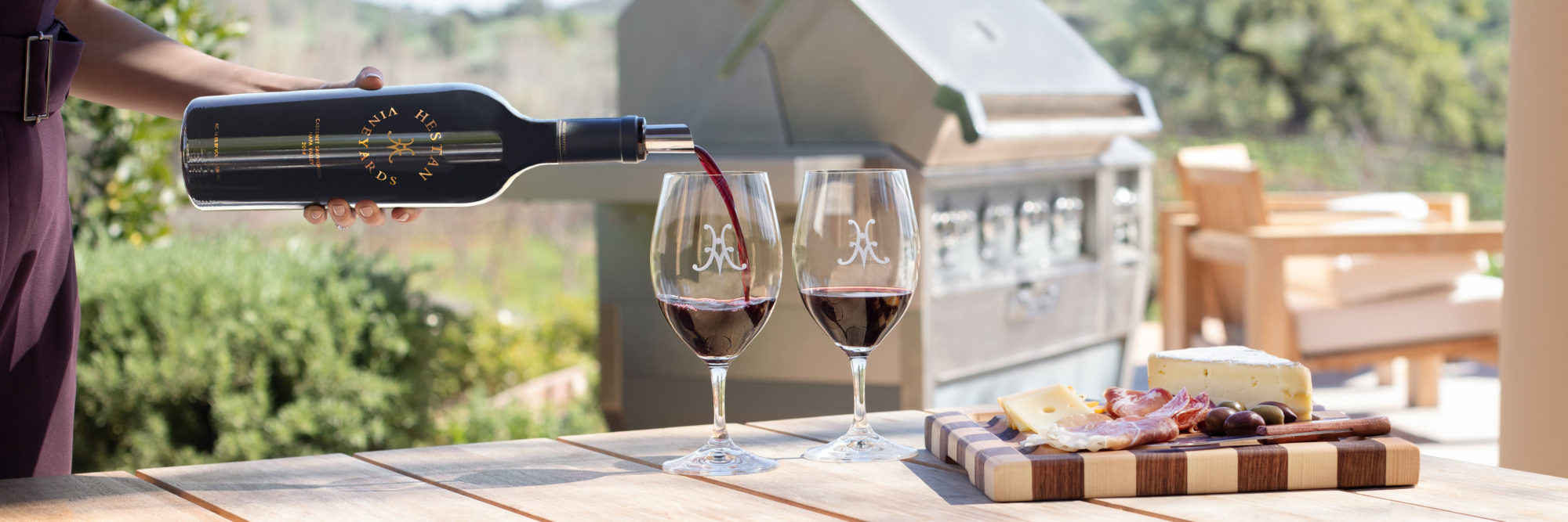 A bottle of Hestan Cabernet Sauvignon being poured at the Esate with a board of meat and cheese.